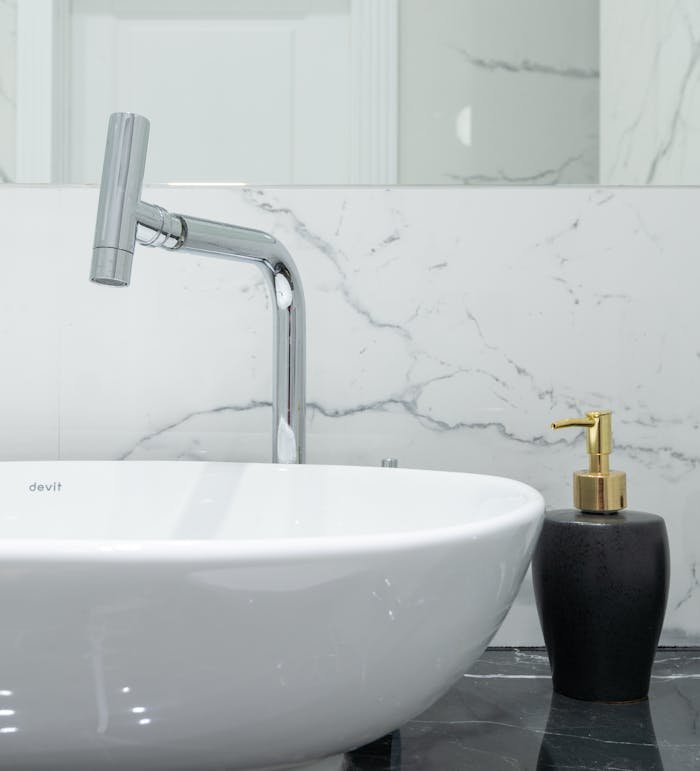 Stylish bathroom featuring a modern chrome faucet, marble backsplash, and a white ceramic washbasin.